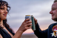 A bride in a flowing wedding dress standing with her partner at Zabriskie Point, the expansive desert landscape of Death Valley unfolding in the background
