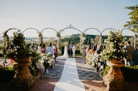 Una coppia di novelli sposi uno di fronte all'altro durante una cerimonia civile simbolica presso la Tenuta Corbinaia, con le splendide colline verdi toscane sullo sfondo.