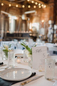 White, black, and green wedding table decorations at an indoor reception