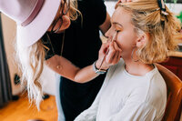 Producer and makeup artist Cassi Angier applies eyeliner to a client on set. 