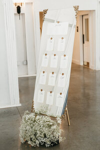 Luxury mirror seating chart with gold wax seals, calligraphy place cards, and baby’s breath floral base, styled for spring wedding at Ashford Acres Inn. 
