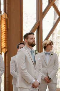 Photo of groom getting choked up while he watches his bride come down the aisle