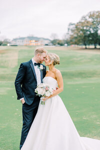 Bride and groom embracing outside in grass