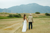 Eastern Idaho Wedding and elopement photograher, photography session. A bride and groom walk hand in hand away from the camera in an outdoor setting.