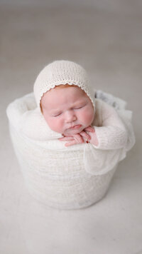 Newborn baby girl in white in a bucket