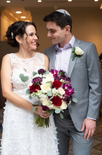 jewish orthodox bride and groom smiling at each other while bride is holding her bouquet at the portico at Mansion at Strathmore in Maryland