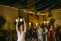 Bride tossing her bouquet during her bouquet toss at her museum wedding venue in Florida, captured by Sarasota wedding photographer Popping Champaign Photography