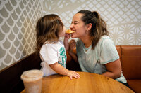 mom and little girl sharing food and smiling at each other