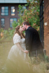 jewish bride kissing and holding hands with scottish groom on the side terrace at District Winery in DC 