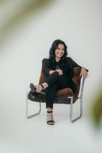A woman sits on a leather chair with her legs crossed.