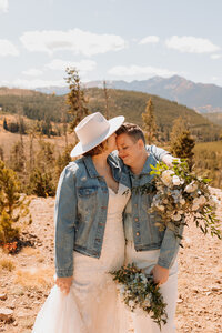 Couple in matching jean jackets kiss and embrace in Rocky Mountain National Park