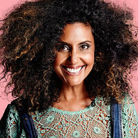 Headshot of beautiful smiling  woman with afro against pink background.