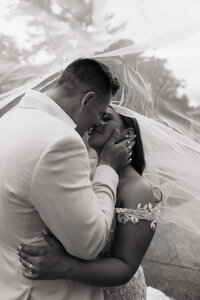 Groom cups bride's face under cover of veil during luxury Minnesota wedding