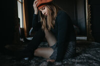 Marcie sits on the floor wearing a red parisian hat.
