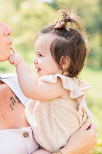 A candid and sweet interaction of a baby touching her mom's face with curiosity and love.