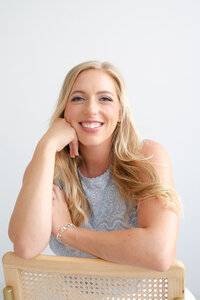 Deborah Jossick, photographer at Oak and Lore Studio, is captured in a candid moment, exuding warmth and creativity. The image showcases her in her studio, surrounded by artistic elements that reflect her passion for photography and her distinctive style