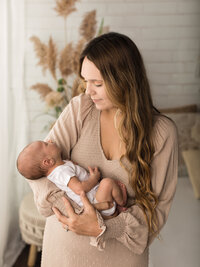 mom holding newborn baby boy for photoshoot