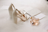 Wedding day details of brides shoes, perfume, and vows.