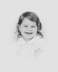 Young girl with curly hair smiles for camera during heirloom portrait session