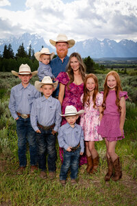 Western-style family portrait at Triangle X Ranch in Jackson Hole, with cowboy hats, denim, and the Grand Tetons in the background.