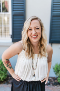 Wendy, owner of the Savannah Elopement Package, smiling in front of a historic home with navy shutters in Savannah, GA.
