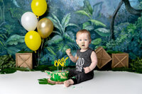 baby boy cake smash against a blue and green polka dot background