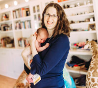 Woman smiling and holding a baby against her chest