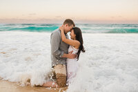 couple embracing in the ocean waves california engagement