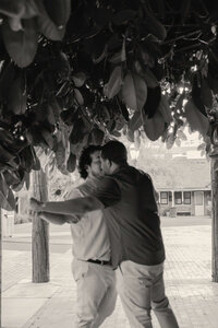 Black and white engagement photo of Arizona couple dancing and embracing under trees.