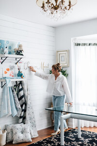 Designer adjusts wall hangings in her artists studio