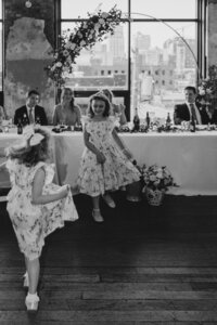 Two flower girls dancing on the dance floor in front of the bridal table at a downtown Kansas City wedding
