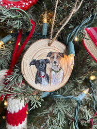 Two dogs painted on a christmas tree ornament