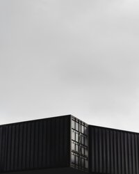 Two shipping containers against sky B&W