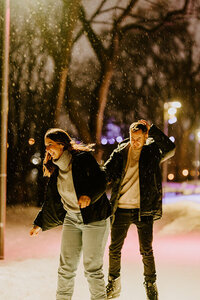 Couple patinant sous la neige, riant ensemble dans un parc illuminé à Montréal, capturé par Laura, photographe couple