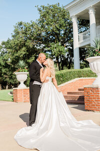 Bride standing on stairs looking down at groom holding her hand