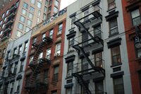NYC apartment buildings with fire escapes and varying architectural styles.