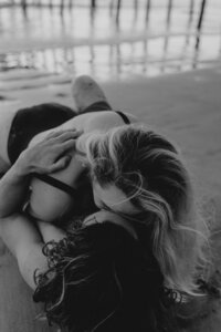 couple shares a kiss on beach in san diego for engagement photos