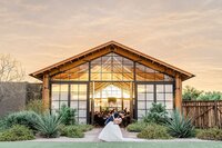 The Paseo Weddings Groom dipping Bride in front of barn at sunset