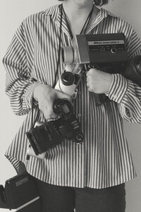 Close-up of photographer's midsection holding various camera gear
