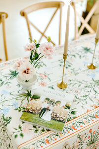 Wedding magazine on floral tablecloth with candles and pink blooms, styled for an elegant Oklahoma wedding