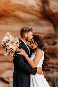 groom kissing bride's forehead