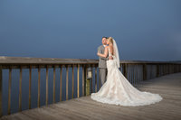 The couple poses for a photo on the pier at The Coastal Arts Center in Orange Beach, Alabama.