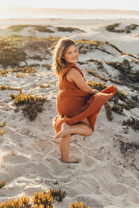 A girl twirls on the Coronado sand dunes during her photography session with Christine Dammann