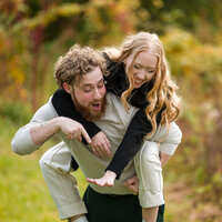 A playful engagement photo of a couple sharing laughs and celebrating their engagement with a focus on the ring.