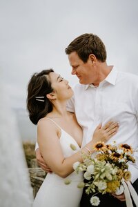 bride and groom kissing on cliffside