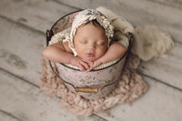 Newborn Photographer, A baby girl sleeps in a  floral patterned pail
