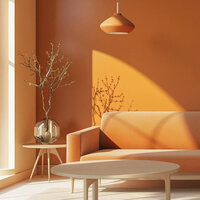 Sunlit modern living room with a peach sofa, round tables, and a glass vase with branches against a warm orange wall.