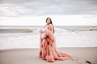 Mom to be in pink gown at the beach near Orlando