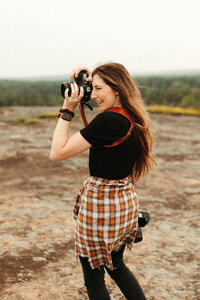 Photographer smiling and holding camera while taking a picture