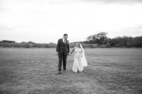 Austin wedding photographer capturing a bride and groom walking in a scenic field with breathtaking beauty.